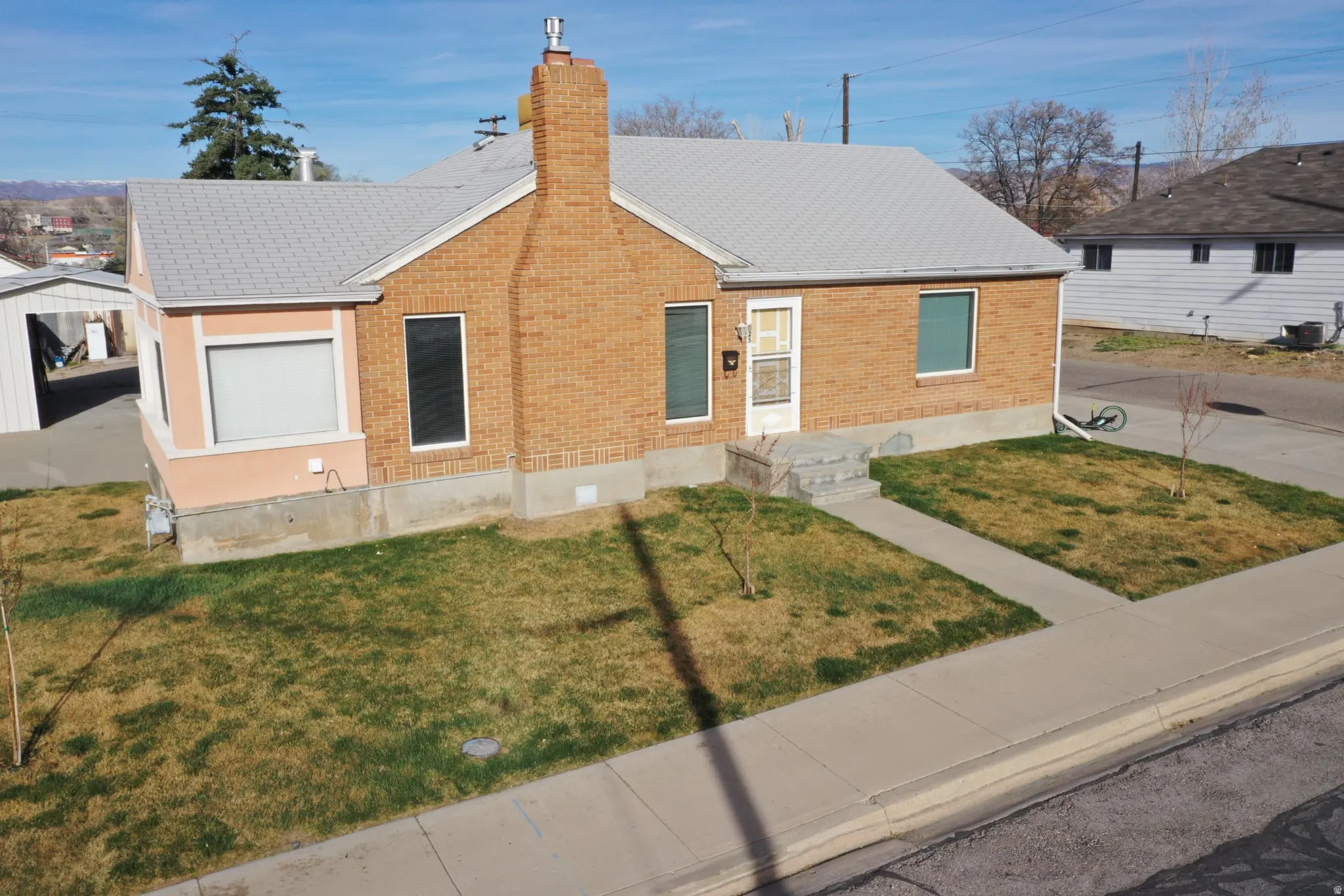 View of front facade featuring brick siding, a front yard, and a chimney