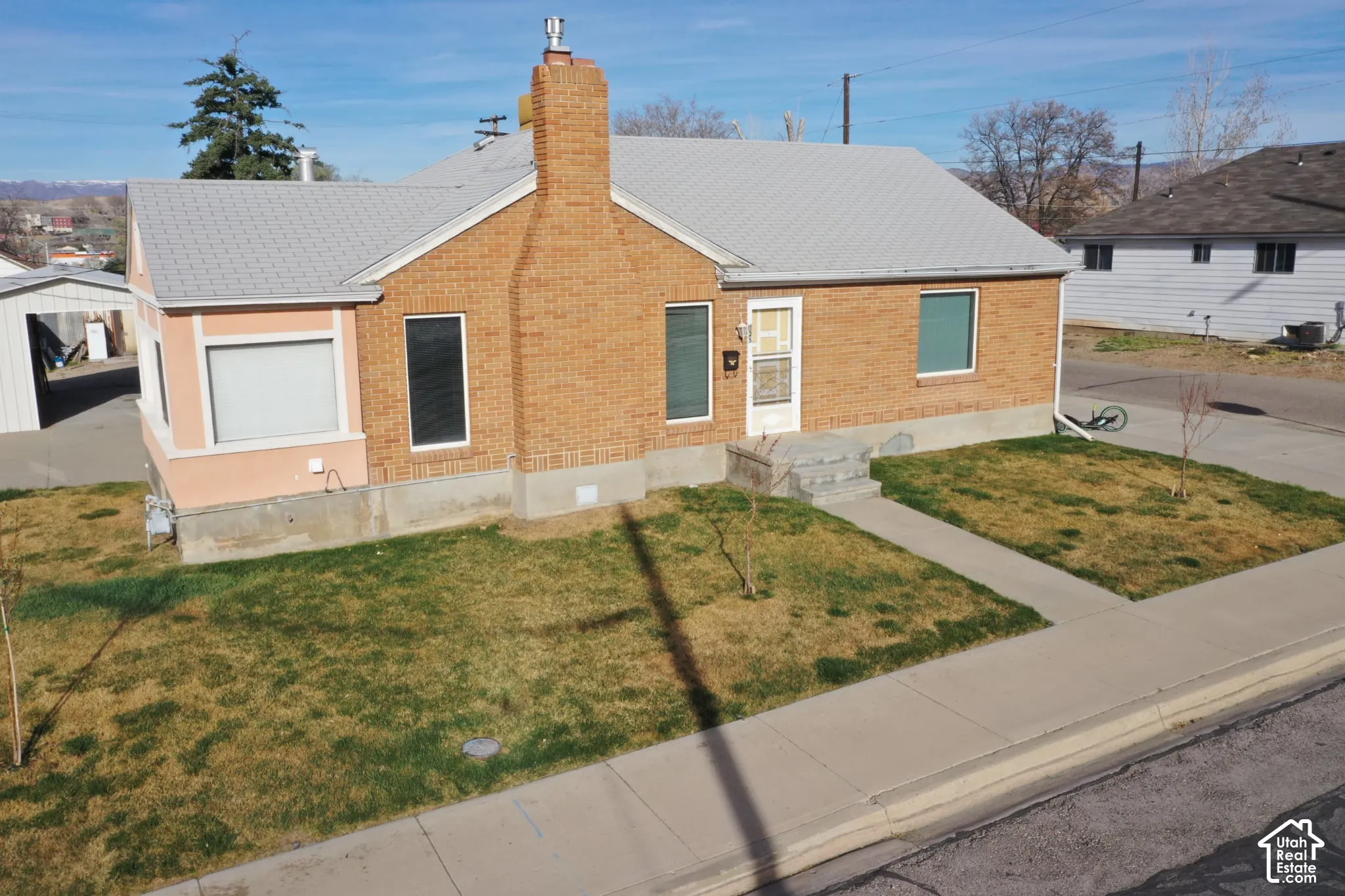 View of front facade featuring brick siding, a front yard, and a chimney