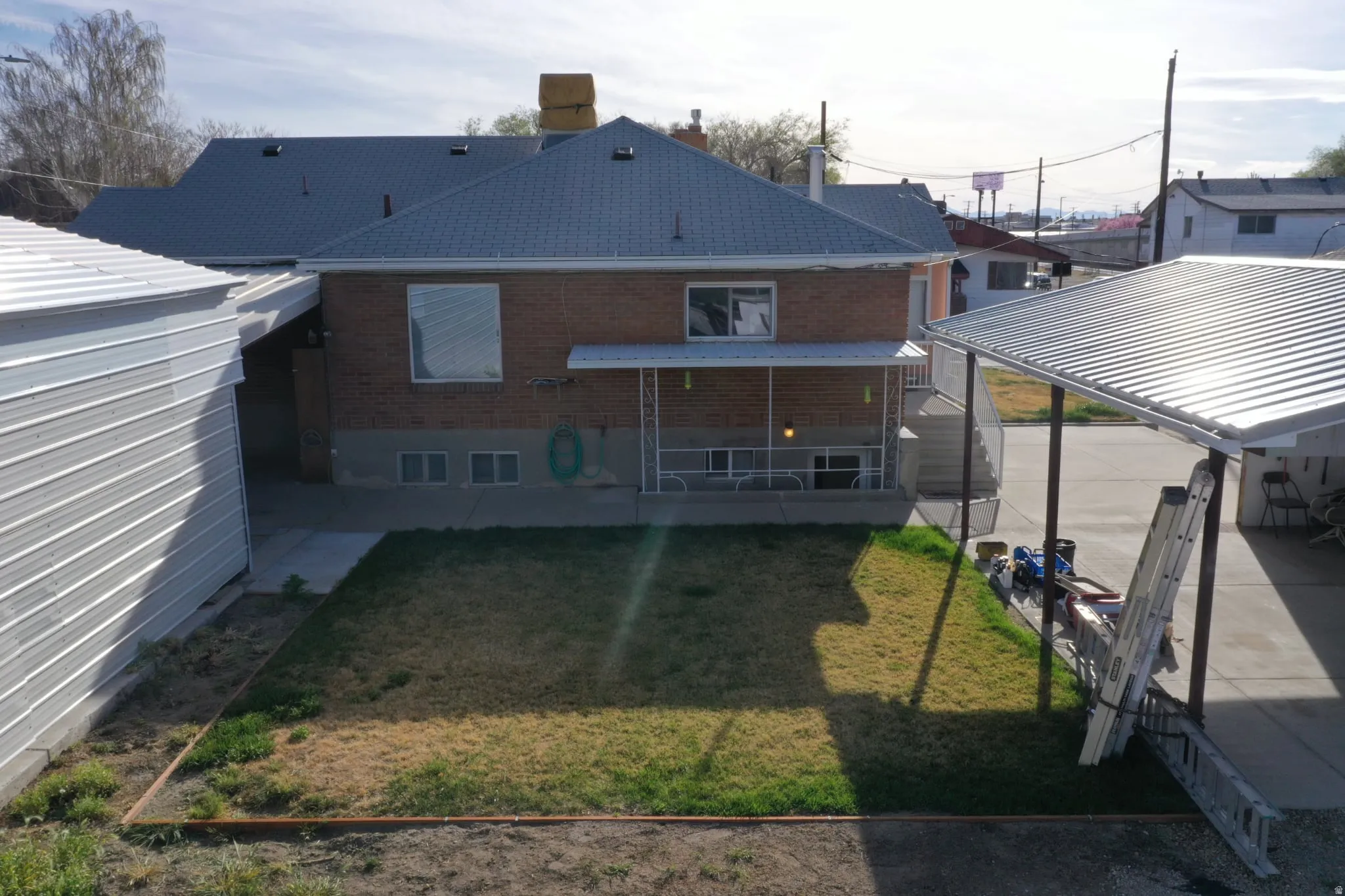 Rear view of house with brick siding, a chimney, and a lawn