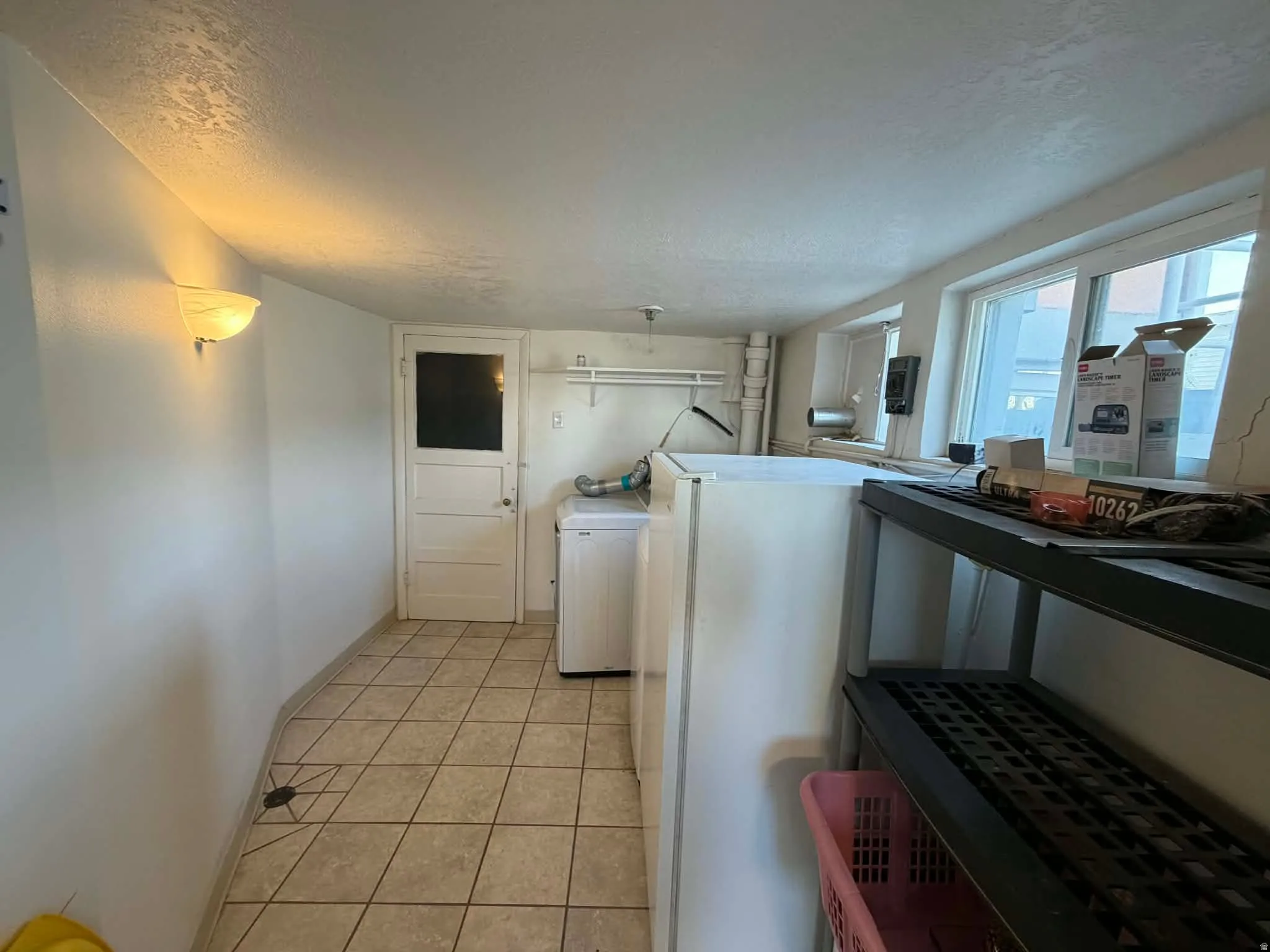 Laundry area featuring a textured ceiling, washer / dryer, and light tile patterned floors