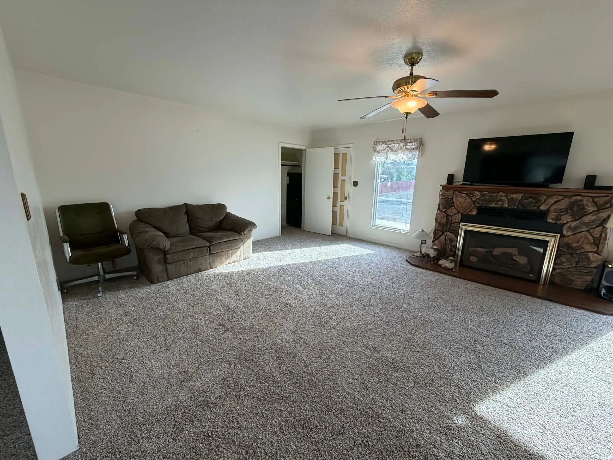 Carpeted living room with a fireplace and a ceiling fan