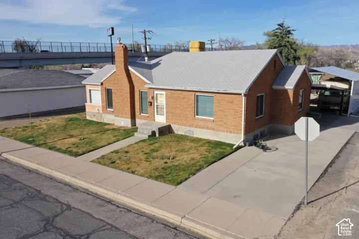 Ranch-style house featuring brick siding, a front lawn, a chimney, and roof with shingles