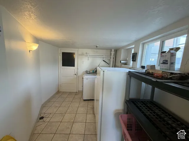 Laundry area featuring a textured ceiling, washer / dryer, and light tile patterned floors