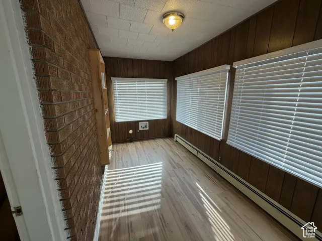 Unfurnished sunroom featuring a baseboard heating unit