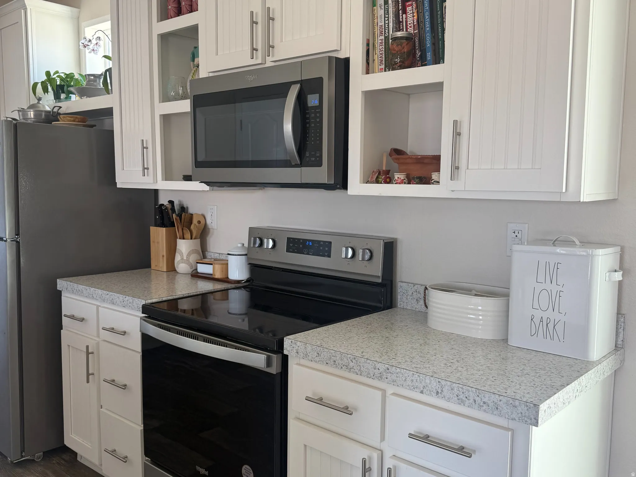 Kitchen featuring stainless steel appliances, light countertops, white cabinets, and dark wood finished floors
