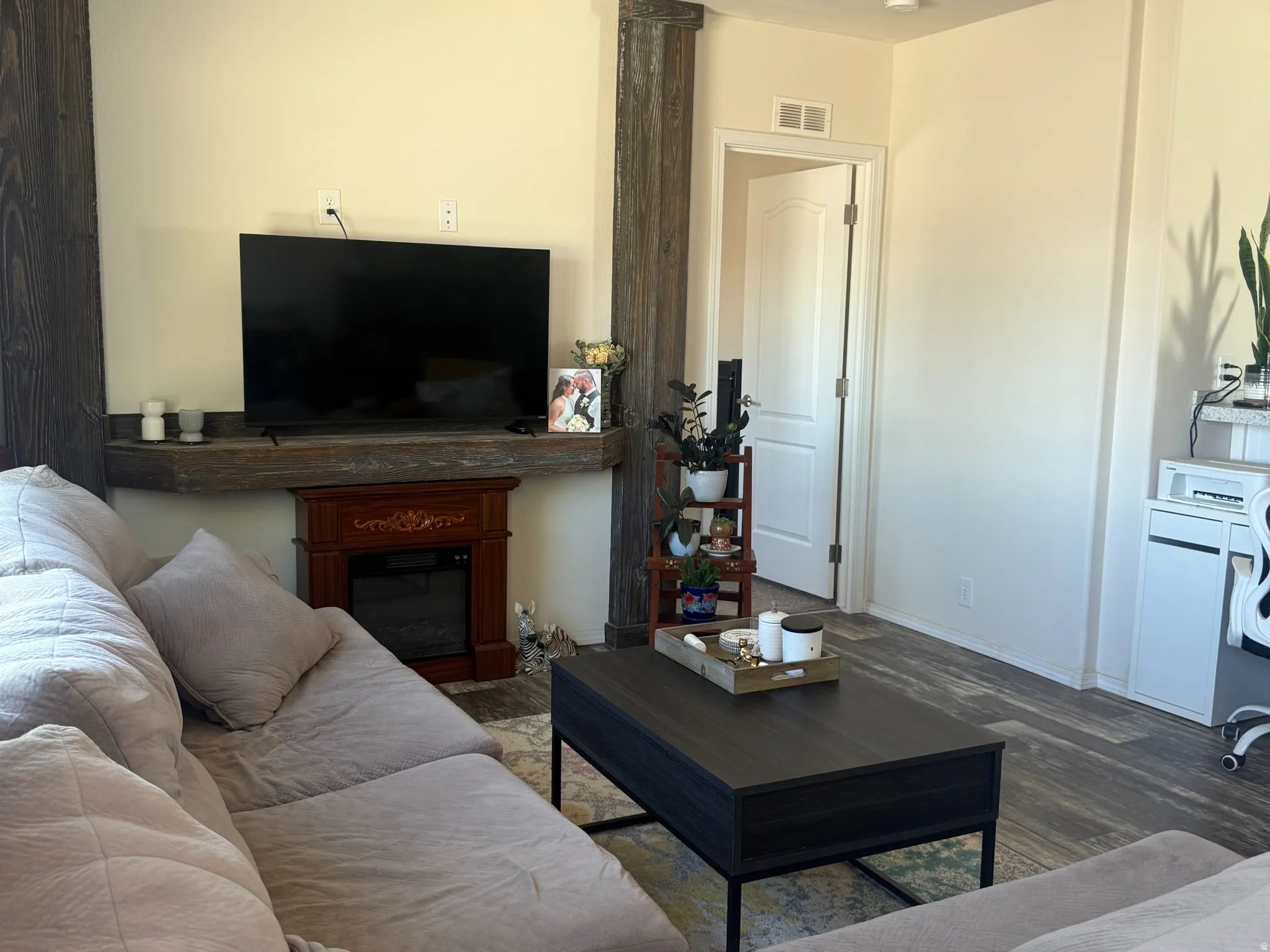 Living room with wood finished floors, a ceiling fan, and a glass covered fireplace