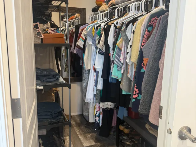 Walk in closet featuring dark wood finished floors located in the primary bedroom