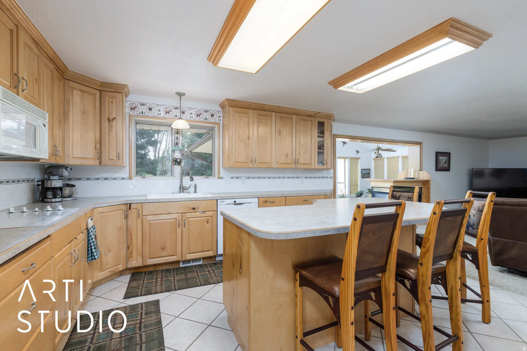 Kitchen with decorative backsplash, a breakfast bar, light countertops, white appliances, and pendant lighting
