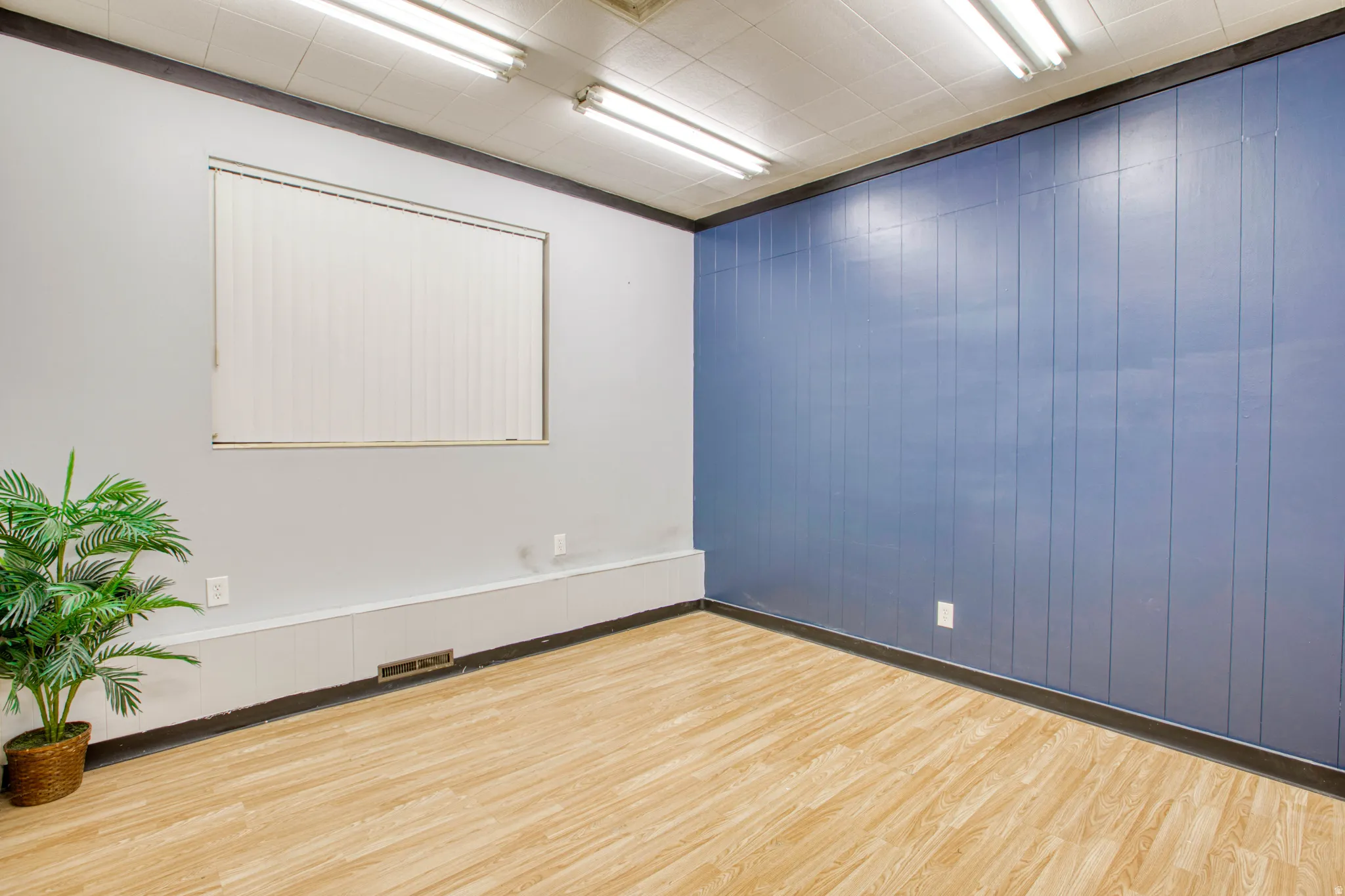 Empty room with light wood-style flooring and wooden walls