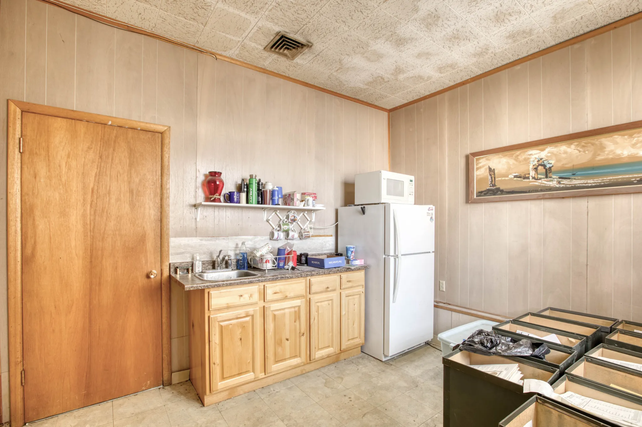 Kitchen featuring light wood finish cabinetry, white appliances, wood walls, open shelves, and light stone countertops
