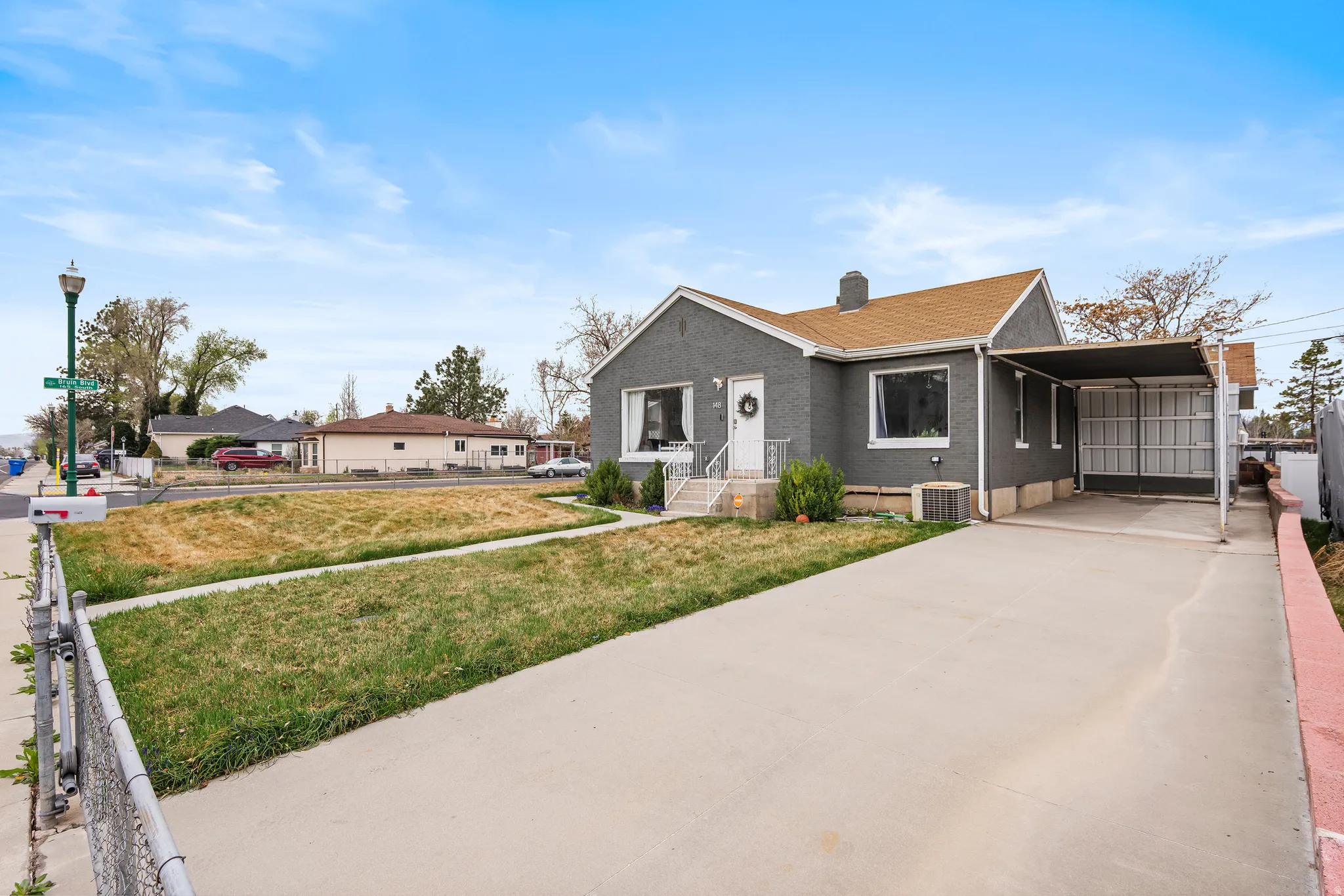 Bungalow-style home featuring a carport, concrete driveway, brick siding, a chimney, and roof with shingles