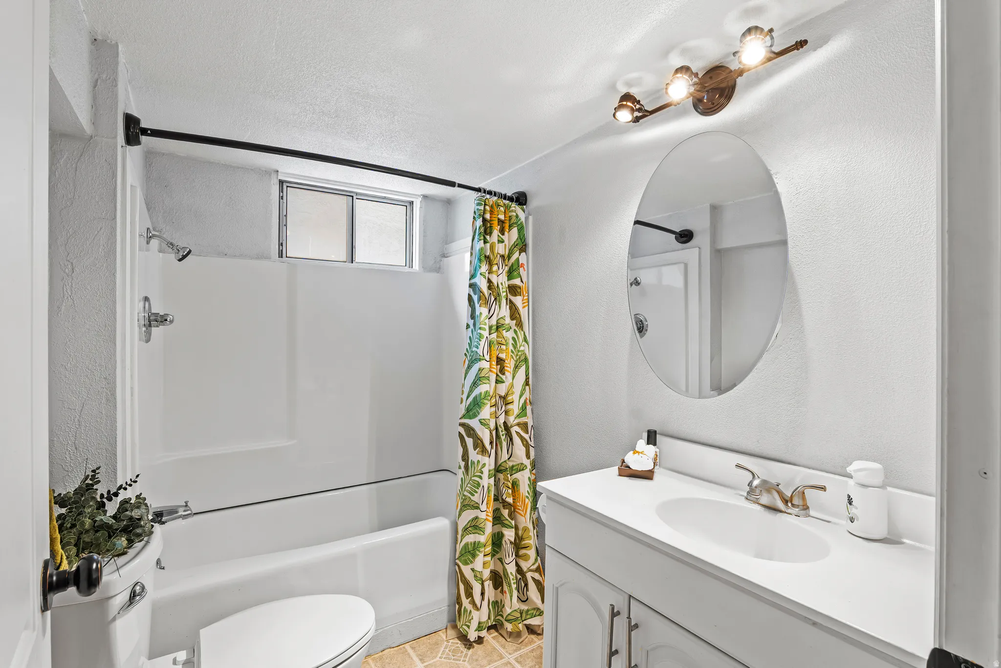 Full bathroom featuring vanity, a textured wall, shower / tub combo, and a textured ceiling