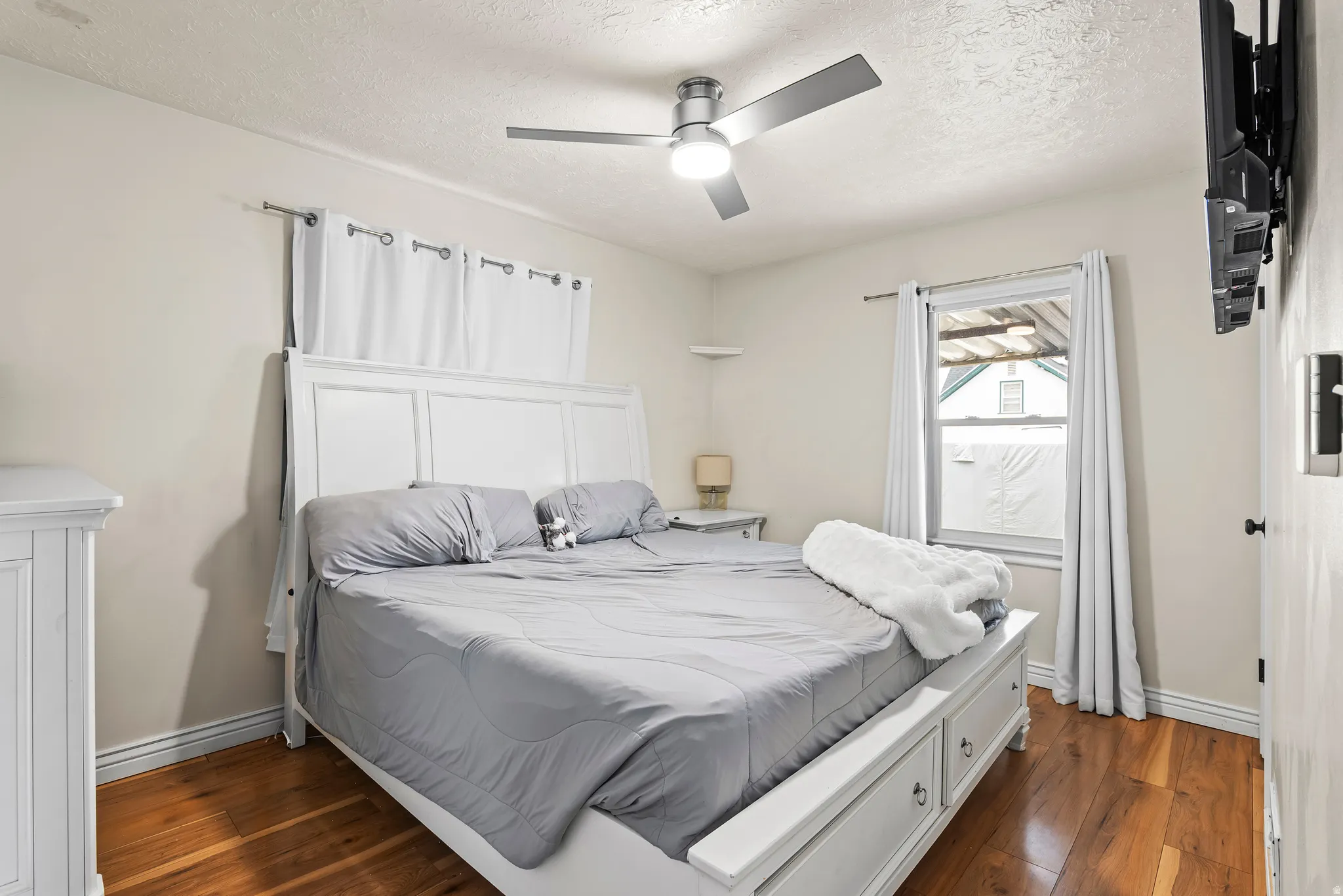 Bedroom featuring a textured ceiling, dark wood-type flooring, and a ceiling fan