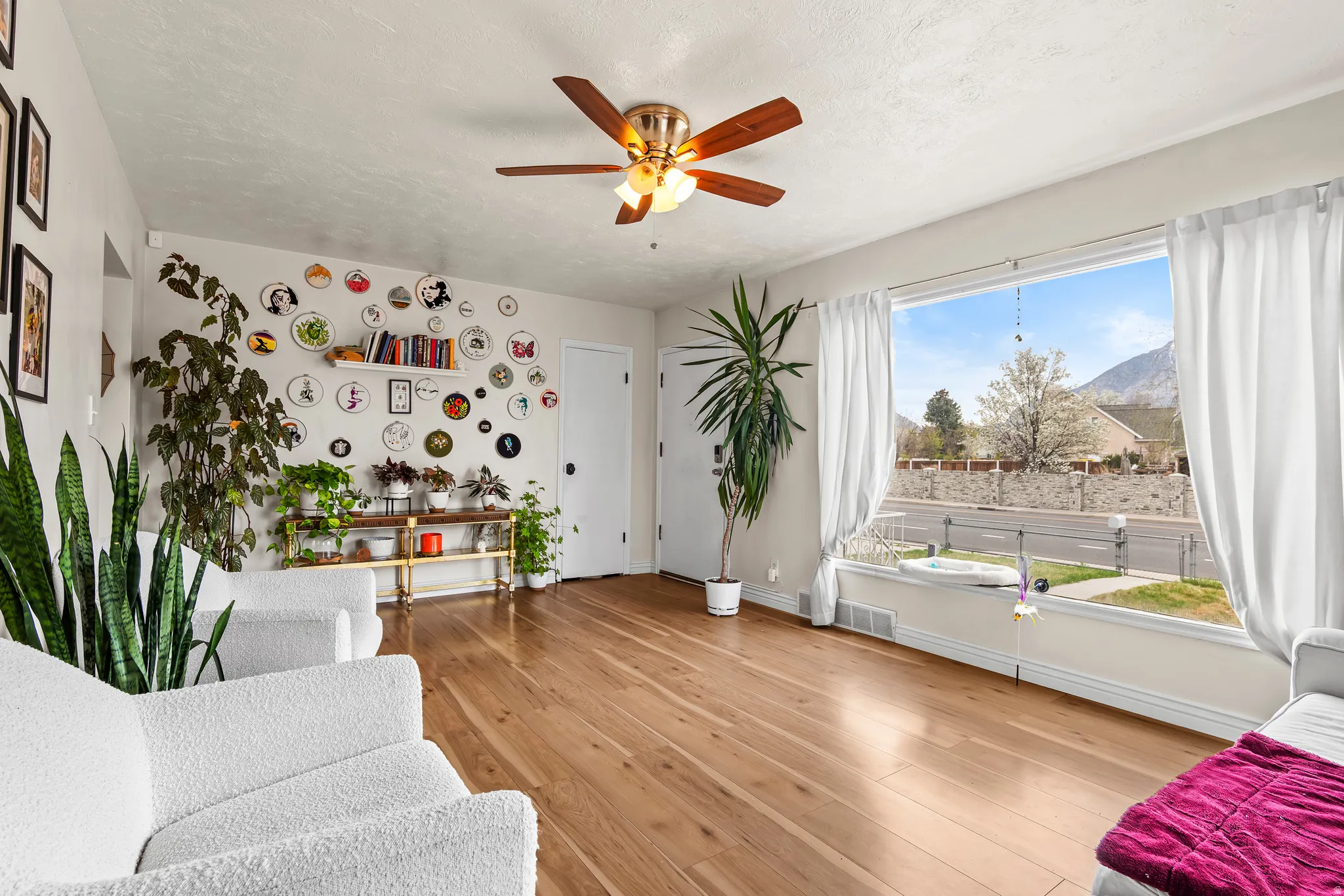 Living area featuring light wood-type flooring, a ceiling fan, a mountain view, and a textured ceiling