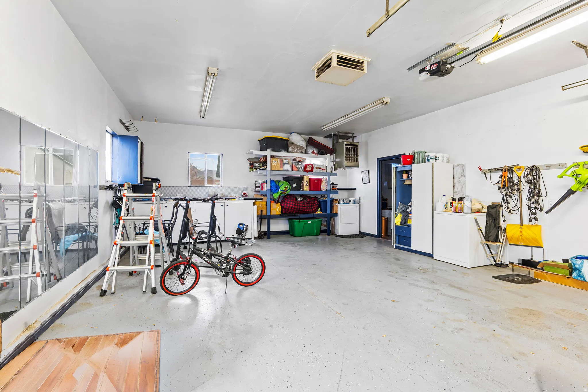 Garage featuring white fridge, a heating unit, and a garage door opener
