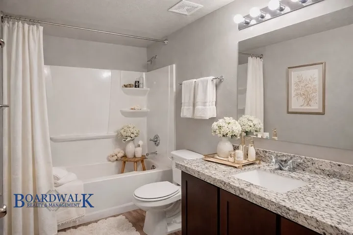 Bathroom featuring vanity, shower / bathtub combination with curtain, and a textured ceiling