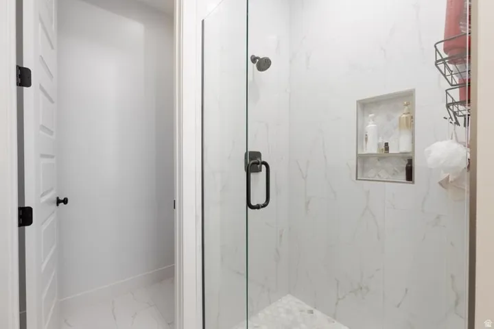 Bathroom featuring a marble finish shower and light marble finish flooring