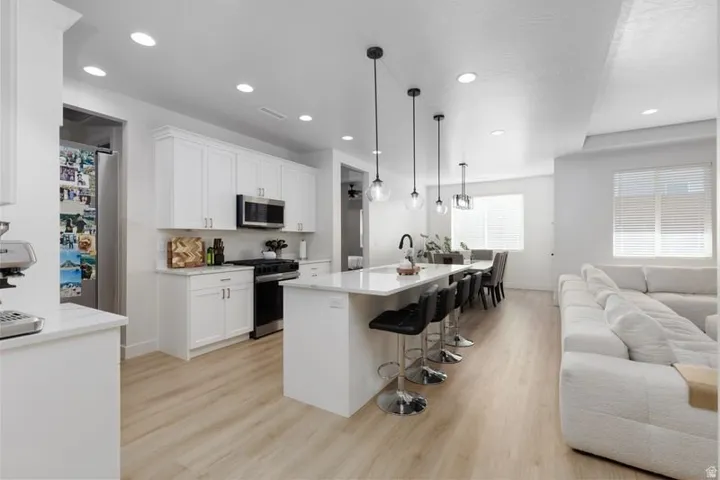 Kitchen featuring open floor plan, a kitchen bar, a kitchen island with sink, light wood-type flooring, and stainless steel appliances