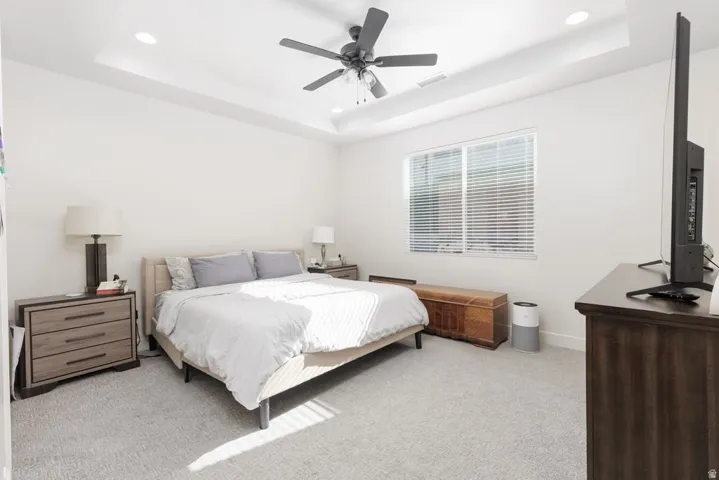 Bedroom featuring light colored carpet, recessed lighting, a raised ceiling, and a ceiling fan