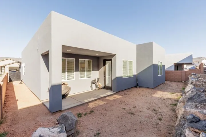 Rear view of house with a fenced backyard, stucco siding, and a patio area