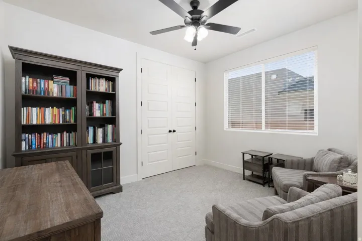 Living area featuring light colored carpet and a ceiling fan
