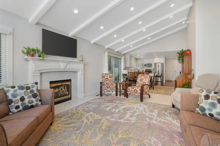 Living room featuring a premium fireplace, vaulted ceiling, and recessed lighting