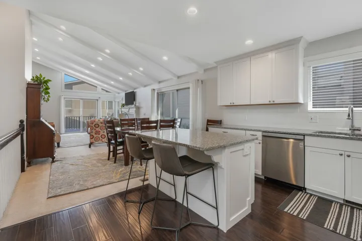 Kitchen featuring stainless steel appliances, white cabinets, a kitchen bar, light stone counters, and a center island