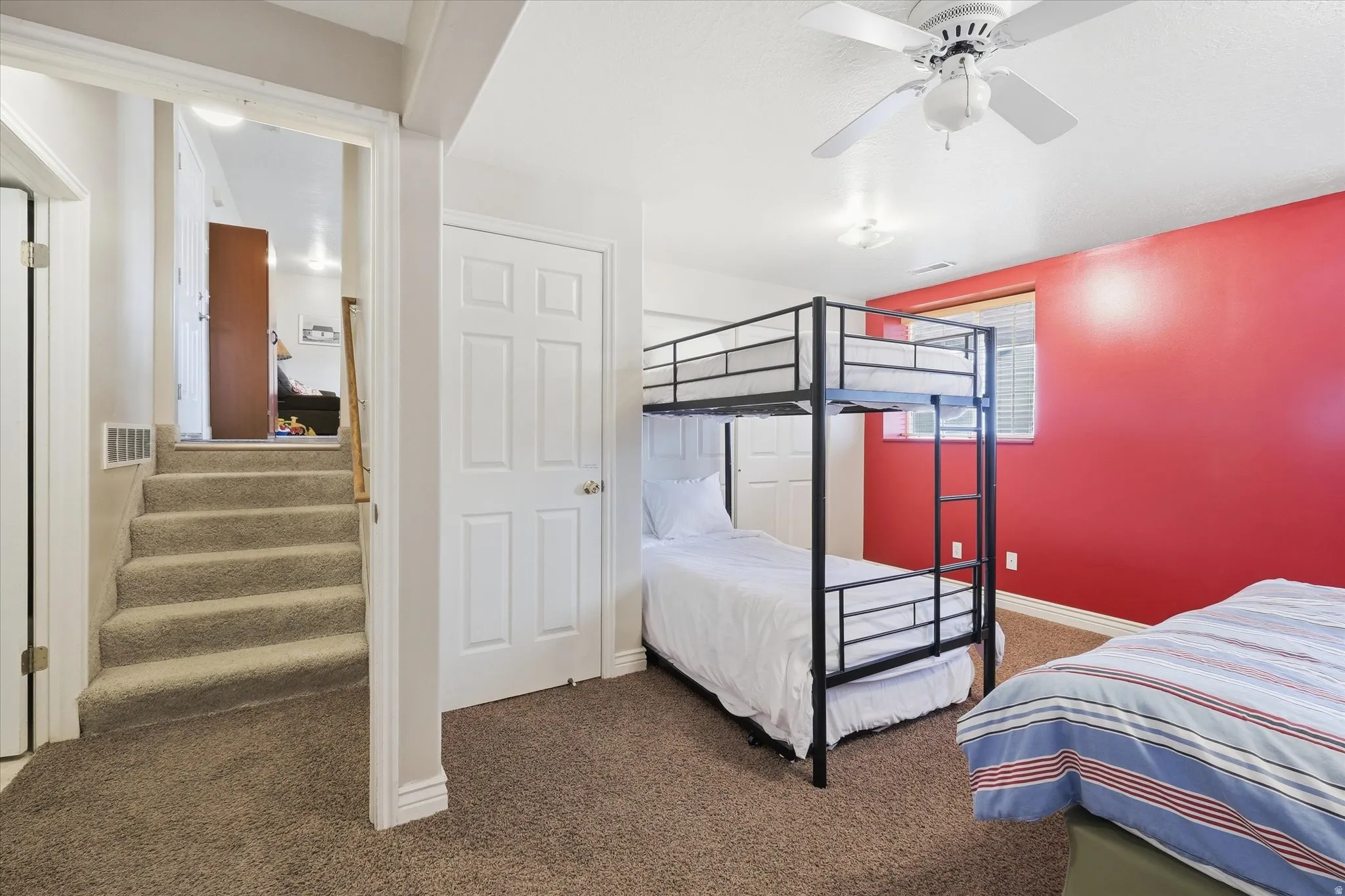 Carpeted bedroom with a ceiling fan and baseboards