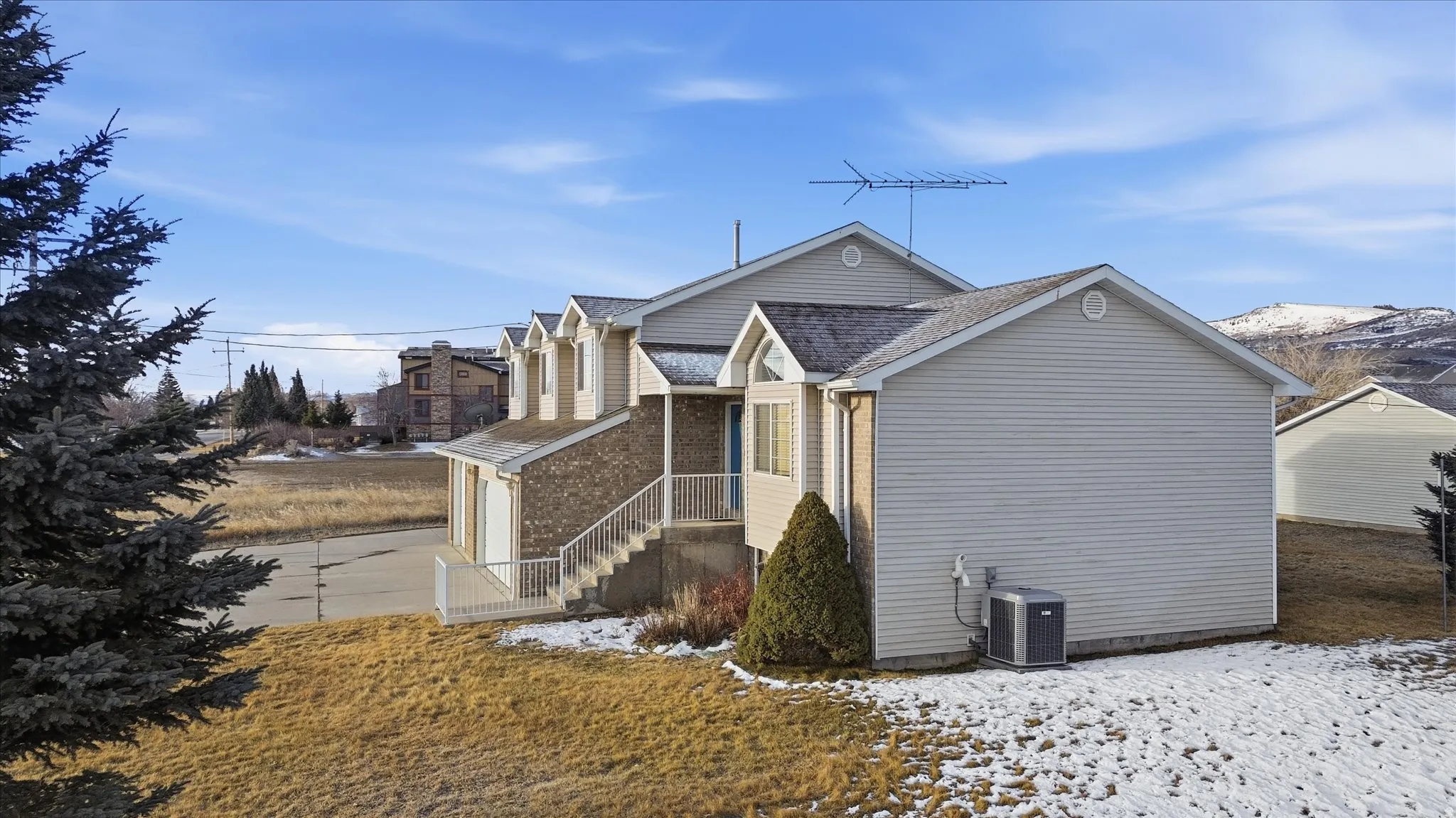 Snow covered property with brick siding and a shingled roof