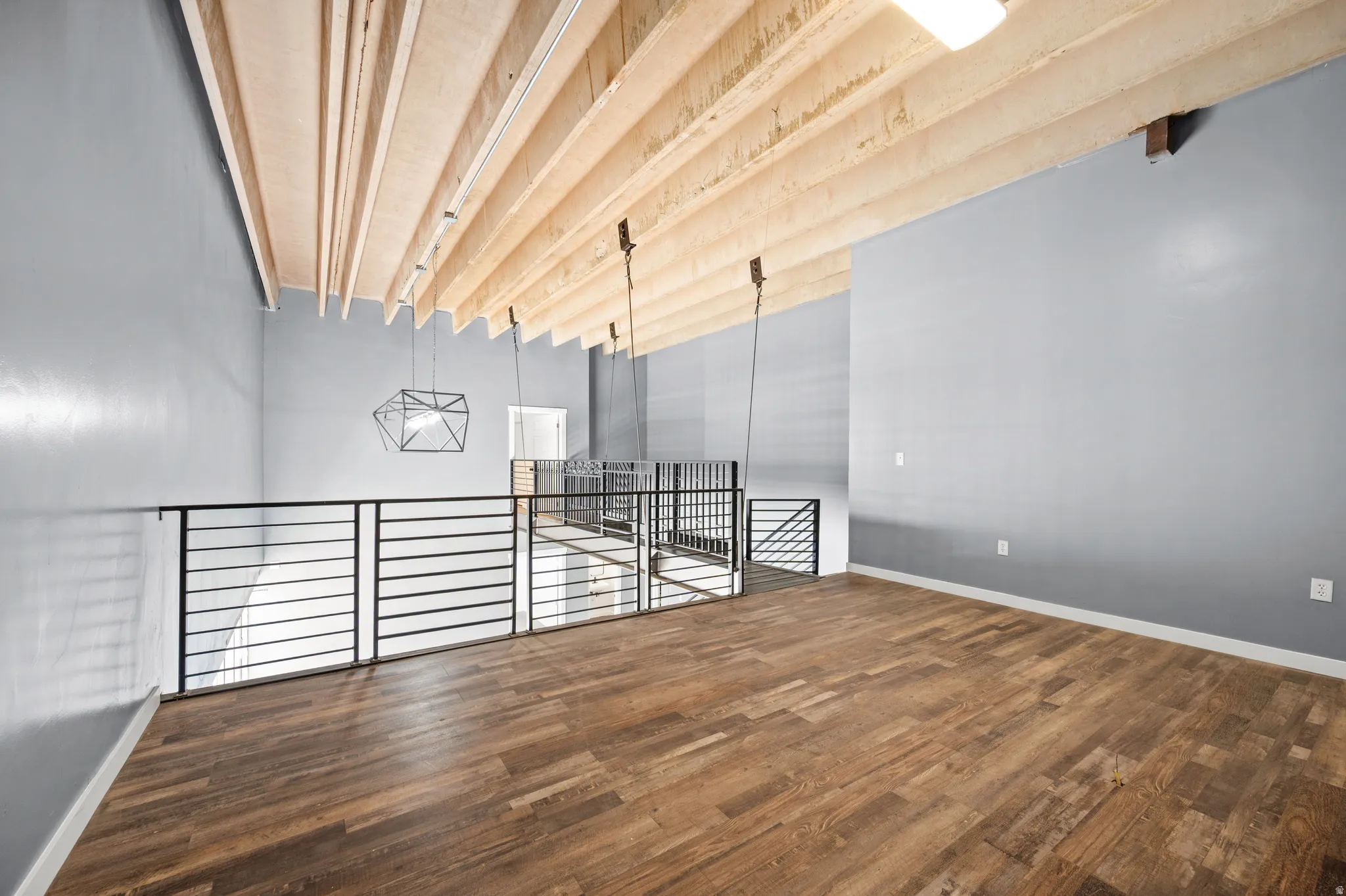 Unfurnished room featuring dark wood-type flooring and beam ceiling