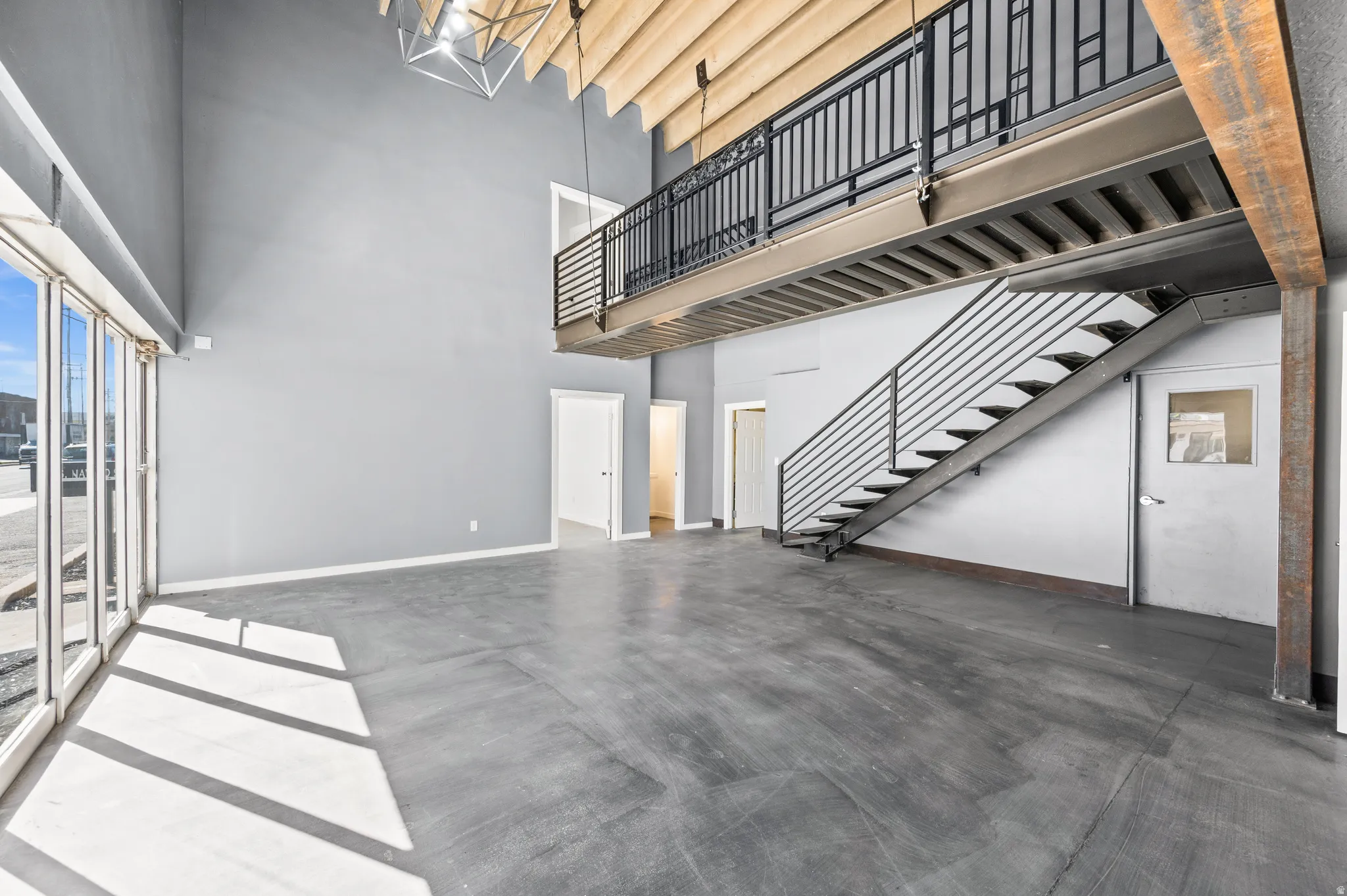 Unfurnished living room with finished concrete flooring and a high ceiling