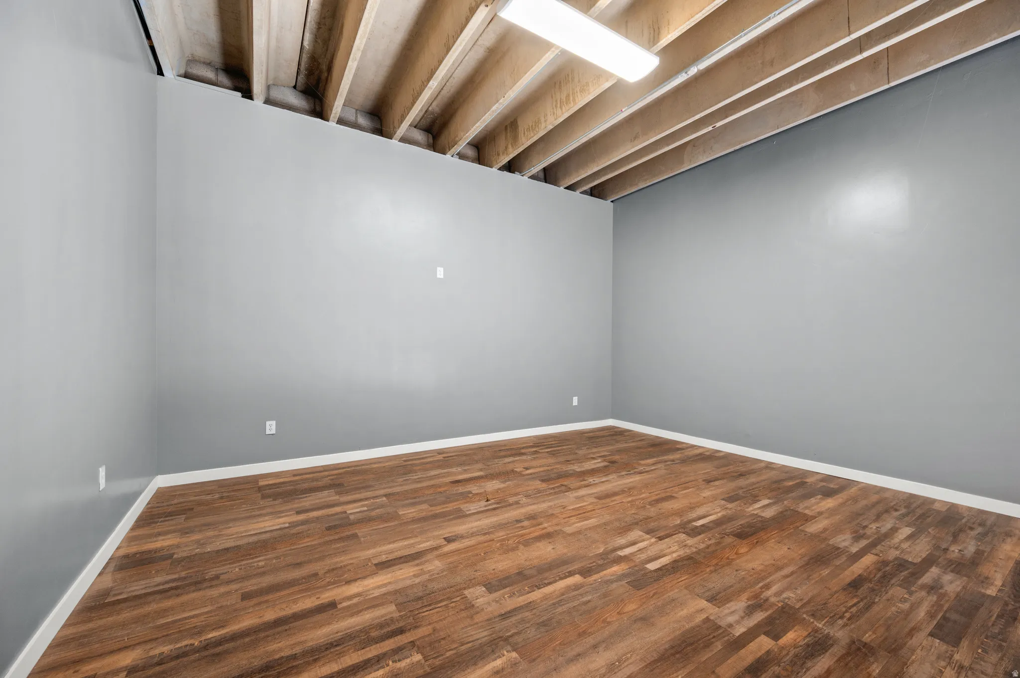 Finished basement with dark wood-style floors and baseboards