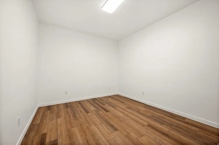 Spare room featuring dark wood finished floors and vaulted ceiling