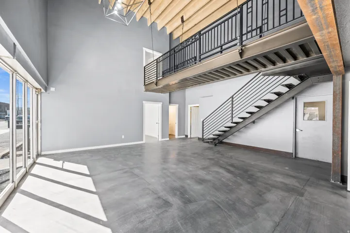 Unfurnished living room with finished concrete flooring and a high ceiling