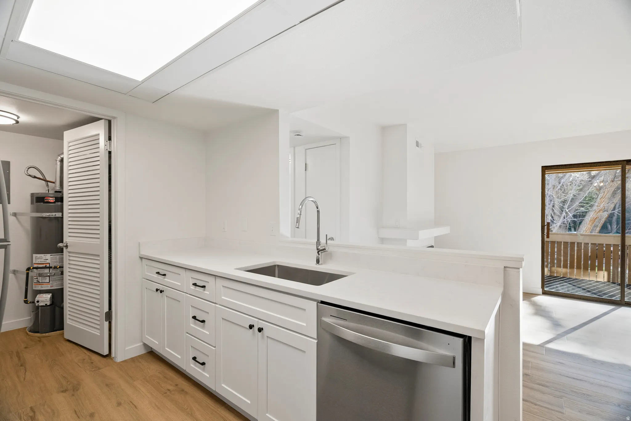 View of kitchen featuring new faucet, sink, and dishwasher. Also shows the entrance to the laundry/utility room