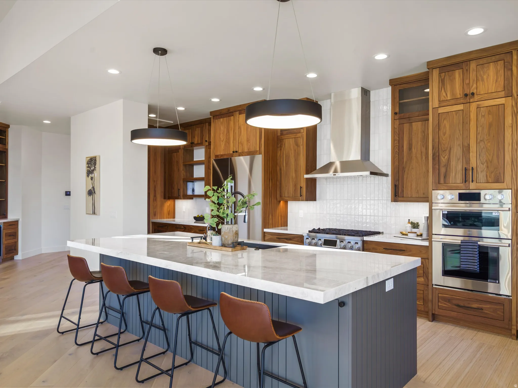 Kitchen with a kitchen breakfast bar, wood finish cabinetry, light wood-style floors, light stone countertops, and a spacious island