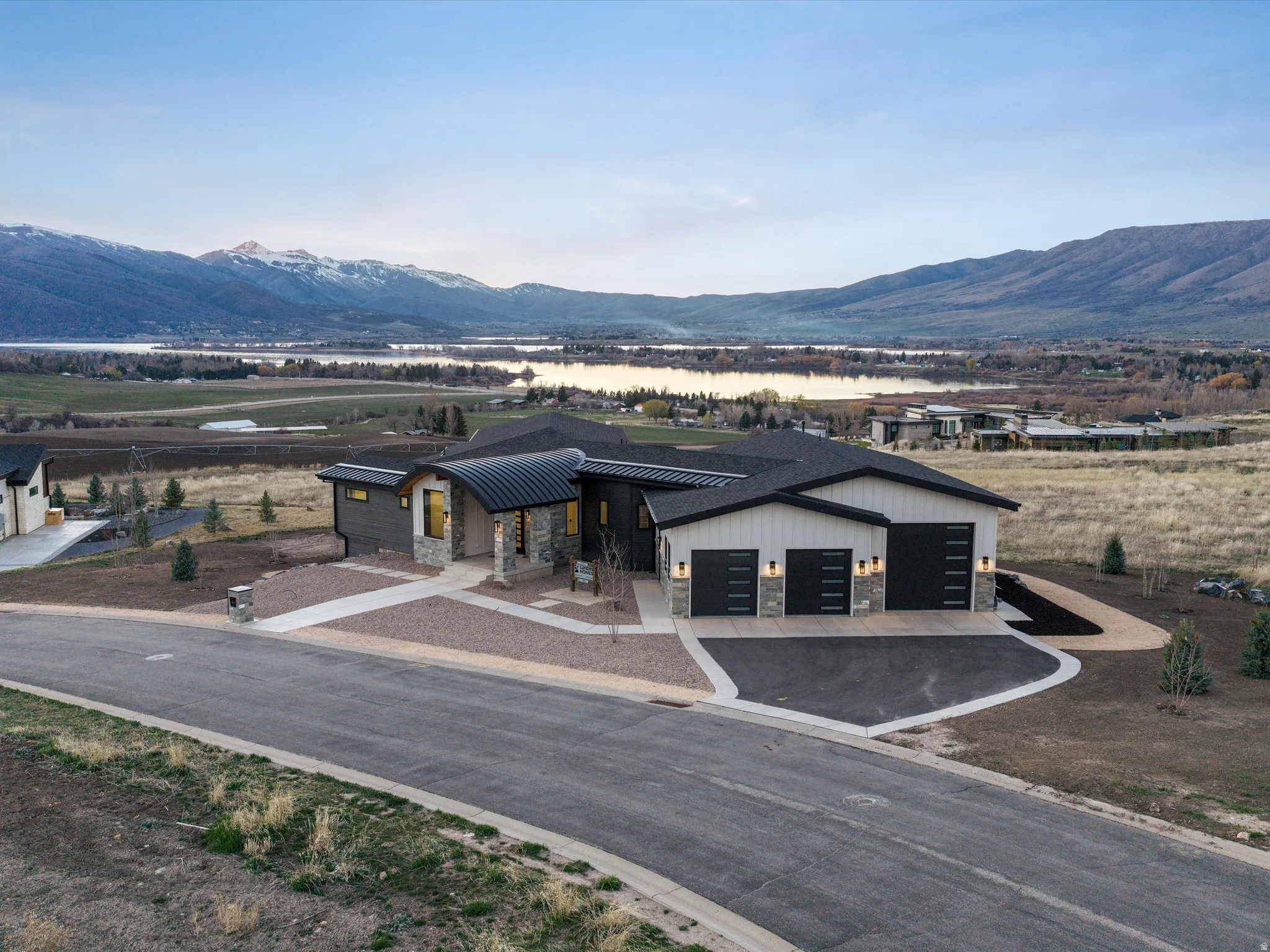 View of front facade with stone siding, a mountain view, a garage, and driveway