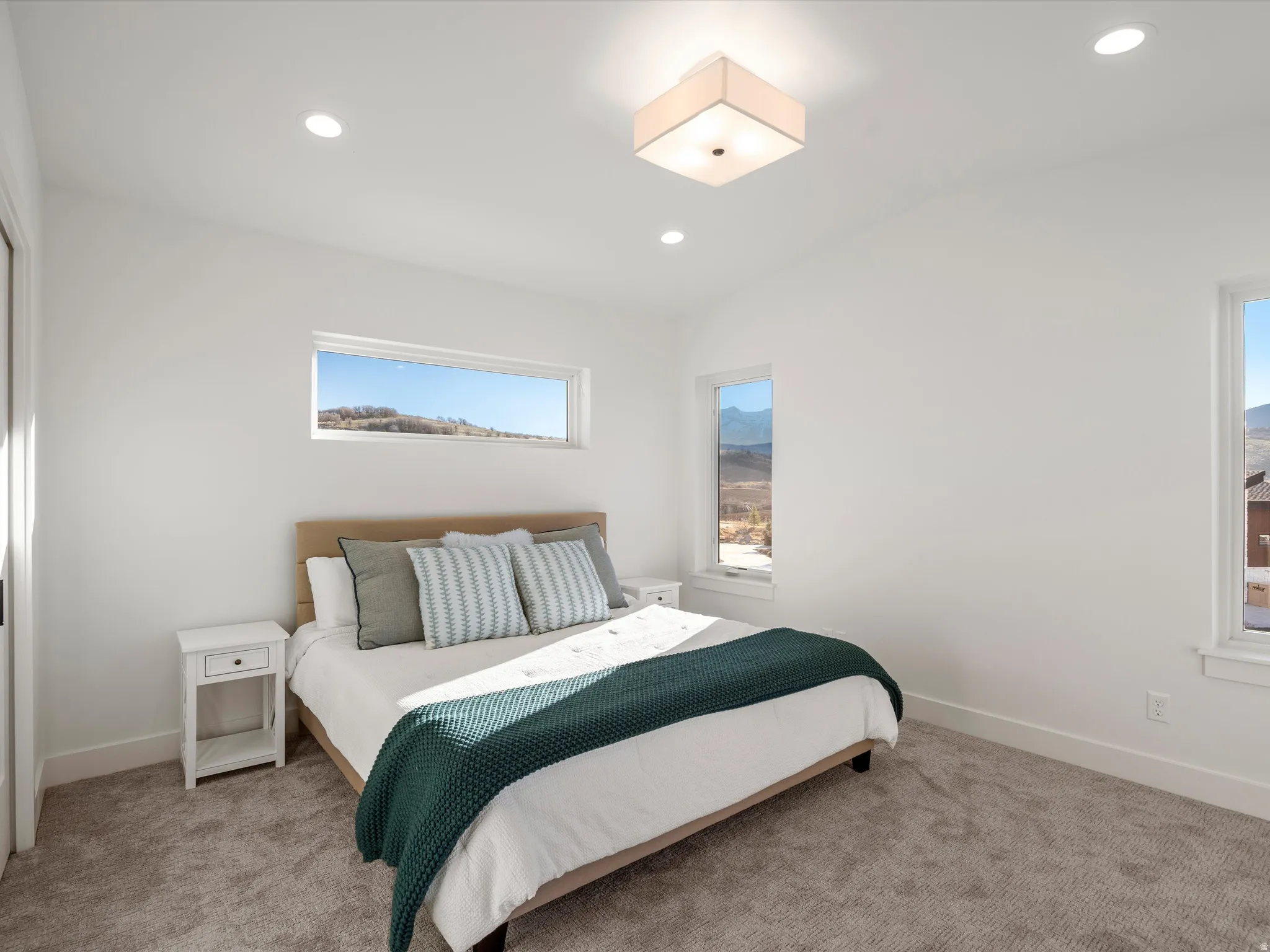 Carpeted bedroom with multiple windows and recessed lighting