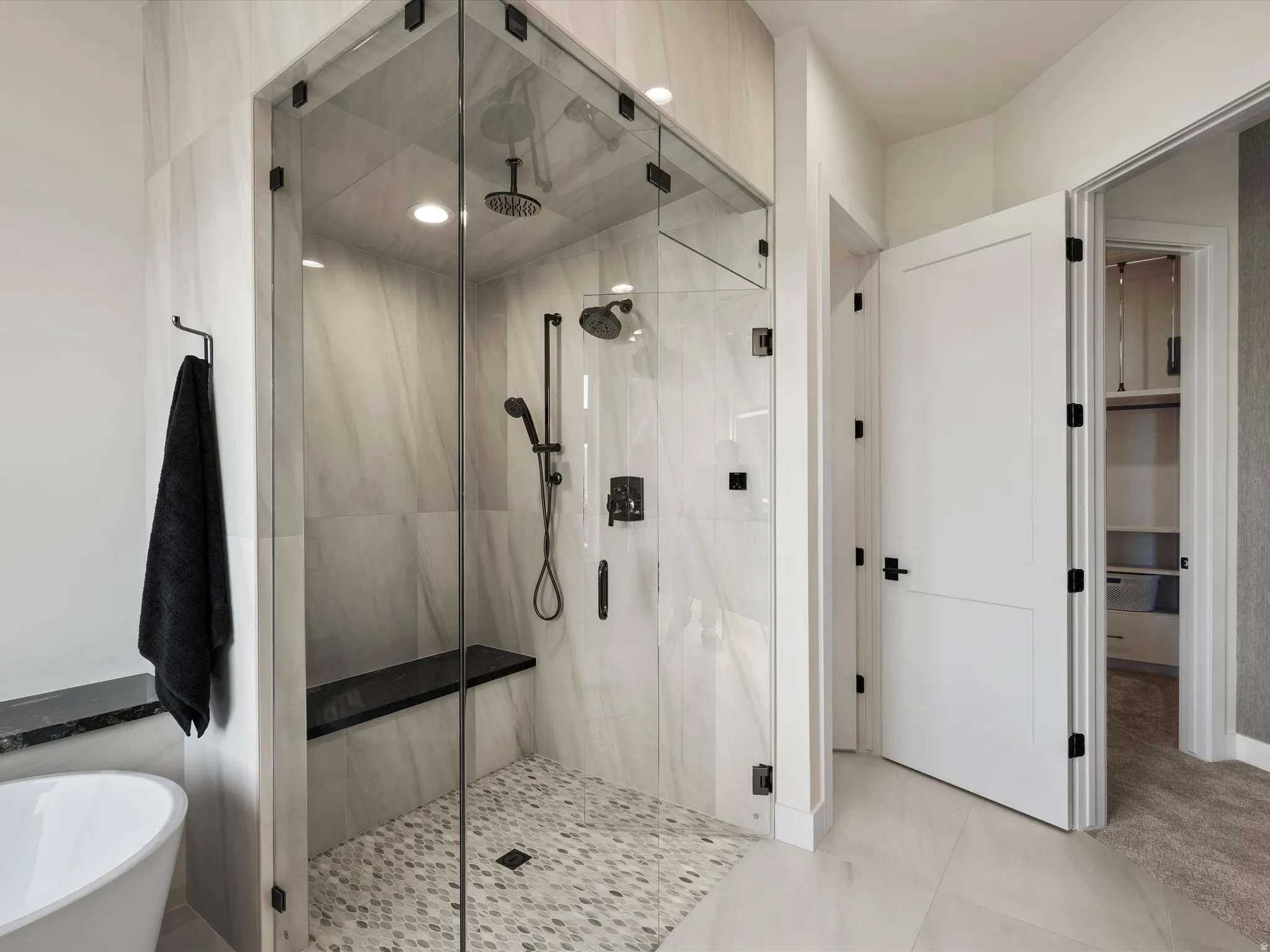 Bathroom featuring a freestanding tub, a marble finish shower, and light tile patterned floors