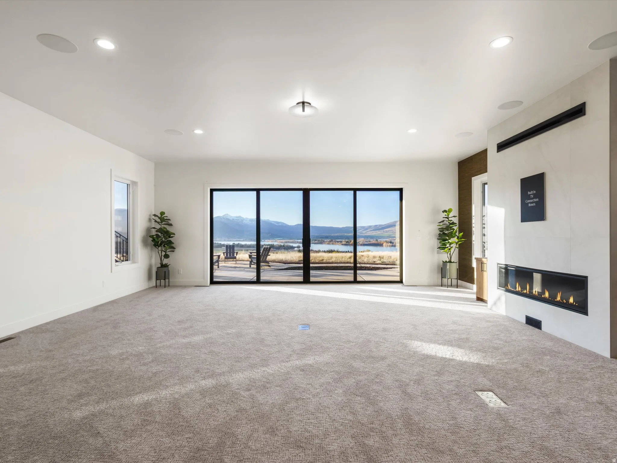 Unfurnished living room featuring a mountain view, carpet, a large fireplace, and recessed lighting