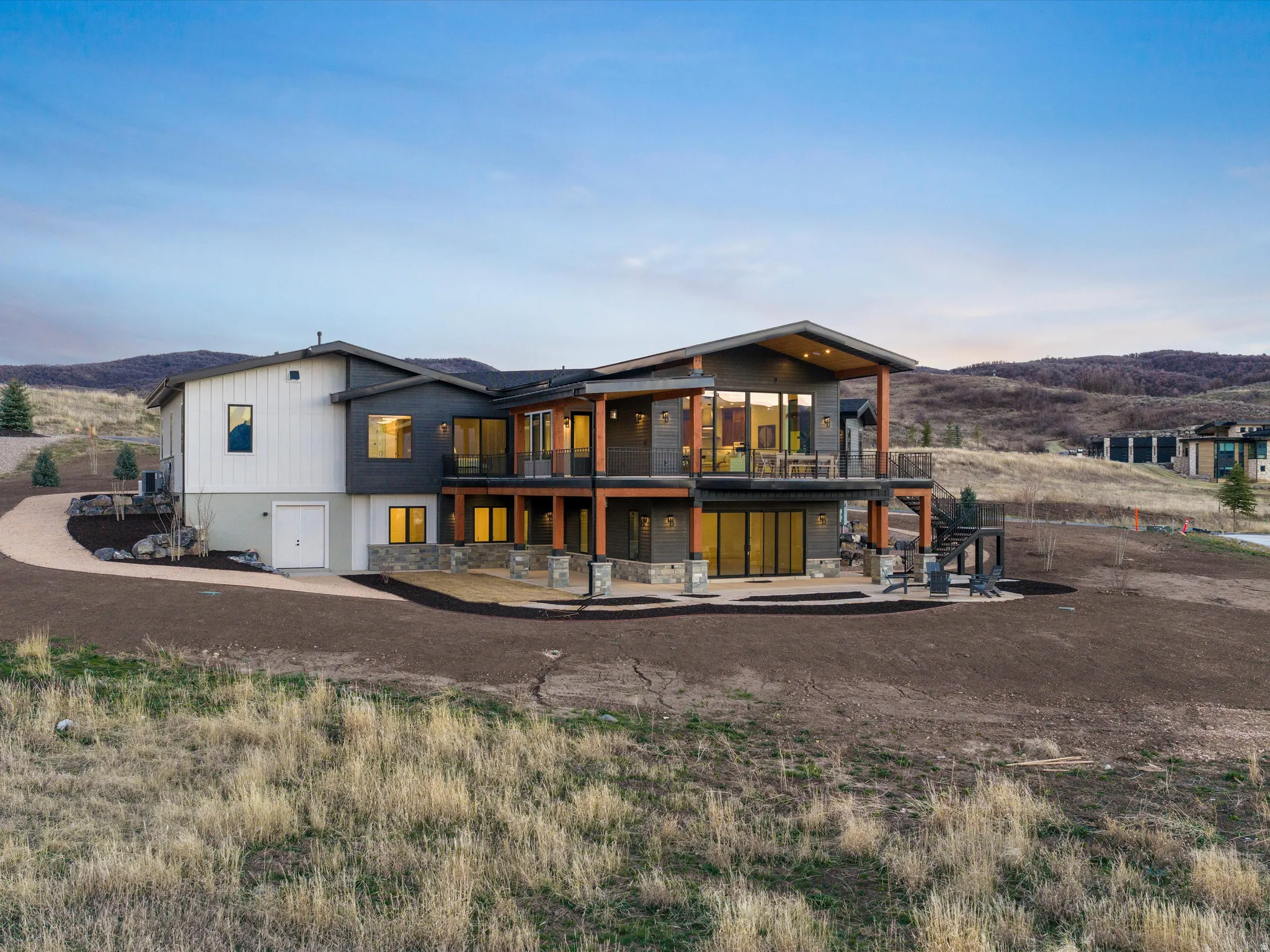 Back of property at dusk featuring a mountain view and a balcony