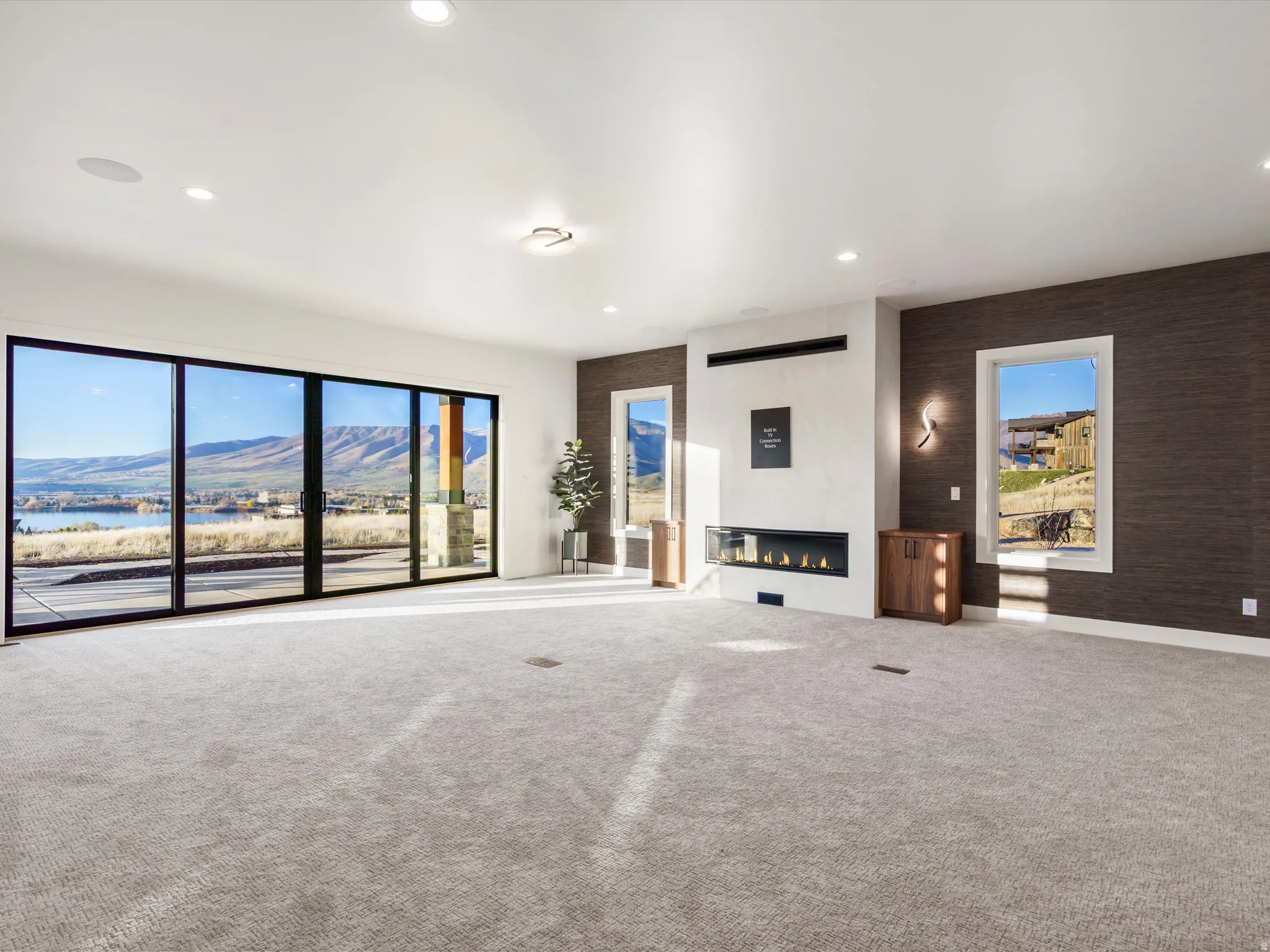 Unfurnished living room featuring a mountain view, an accent wall, carpet, recessed lighting, and a fireplace