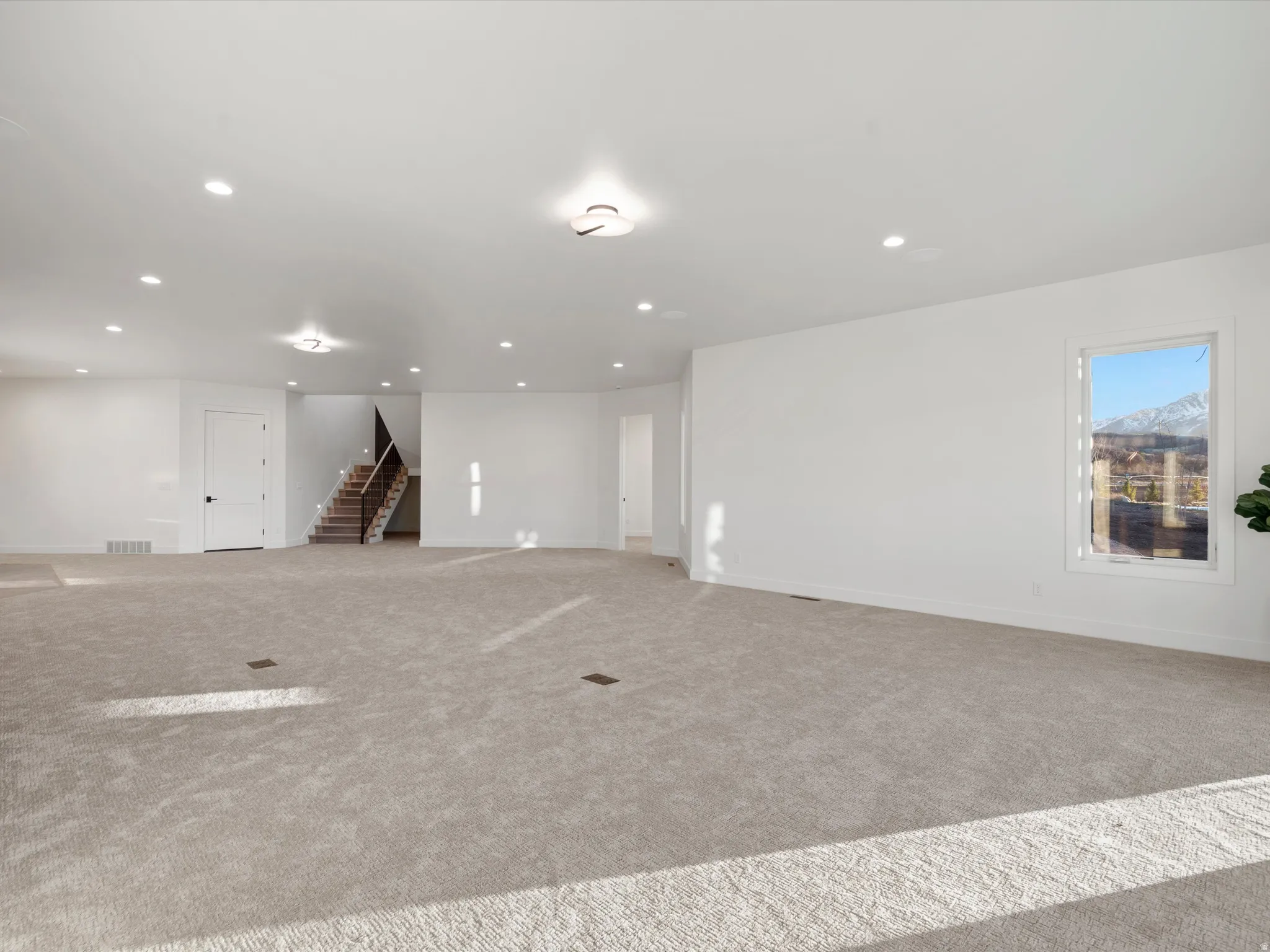 Empty room with light colored carpet and recessed lighting
