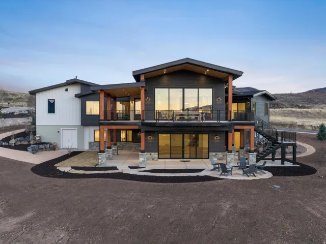 Back of property featuring a balcony and stone siding