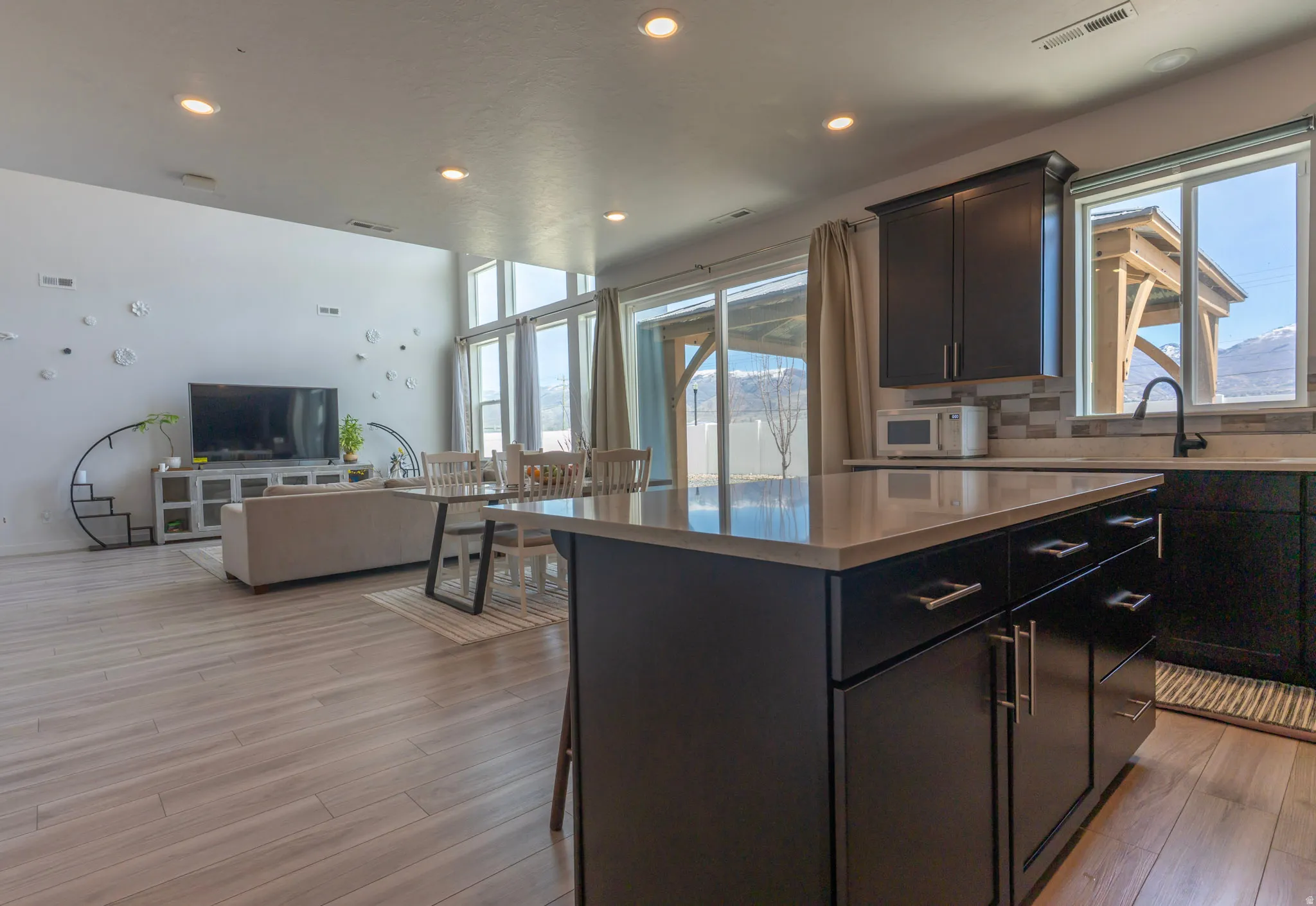 Kitchen featuring open floor plan, light wood-type flooring, a kitchen island, a breakfast bar, and recessed lighting