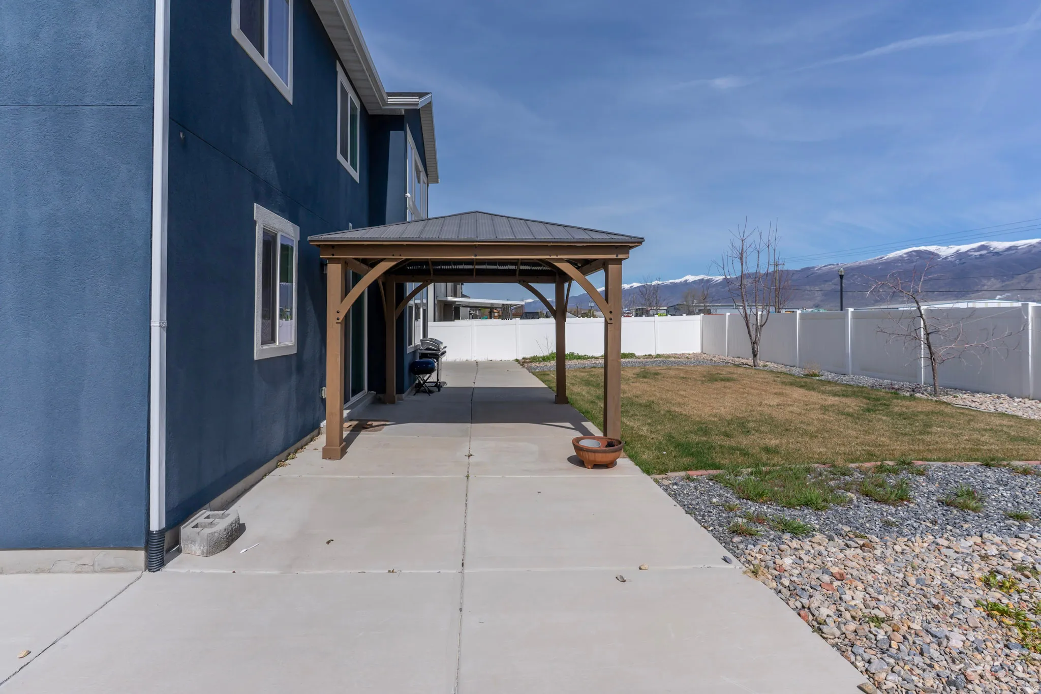 Fenced backyard featuring a mountain view, a gazebo, and area for grilling