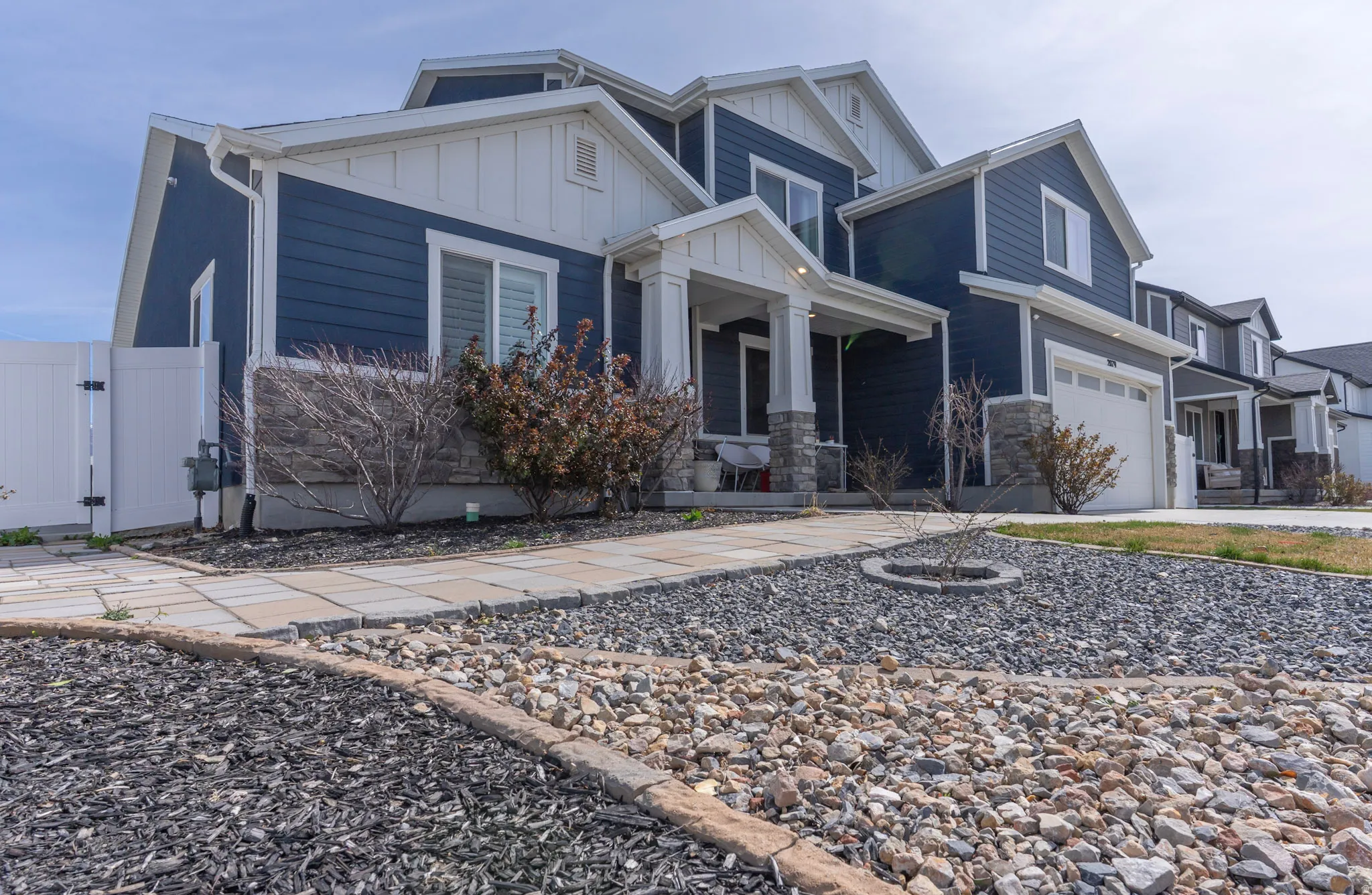 Craftsman house featuring board and batten siding, an attached garage, a gate, driveway, and stone siding