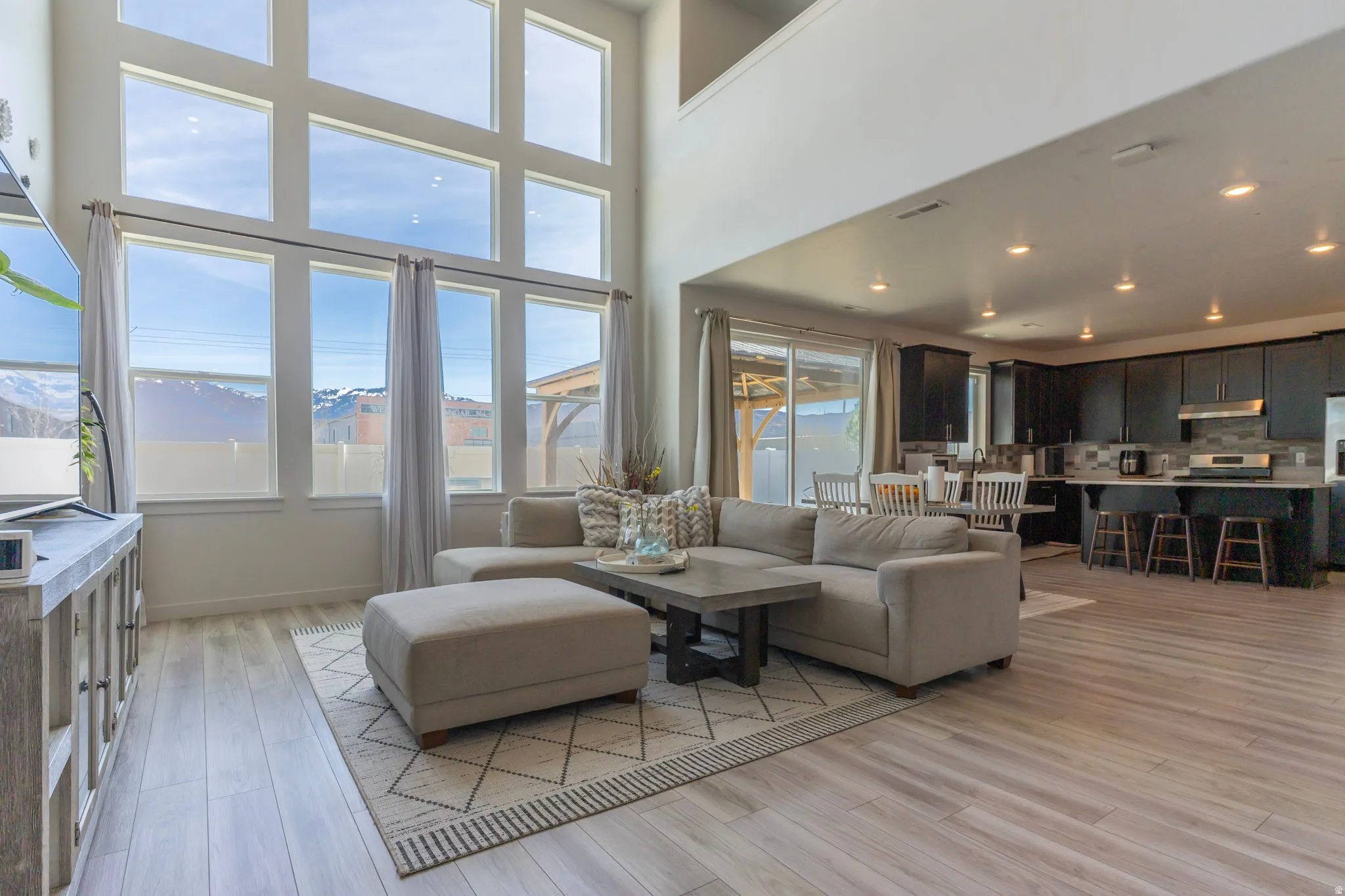 Living area with light wood-type flooring, a high ceiling, and recessed lighting