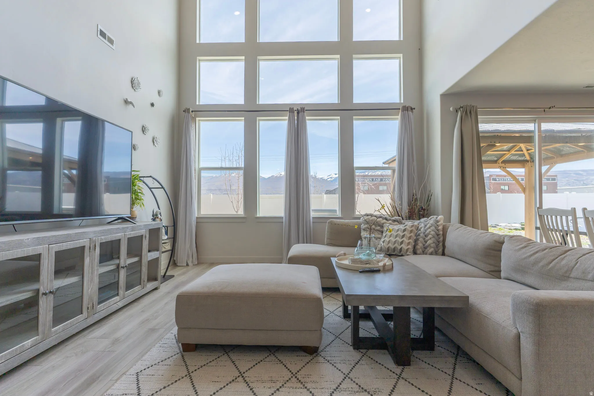 Living room featuring a high ceiling, light wood finished floors, a mountain view, and plenty of natural light