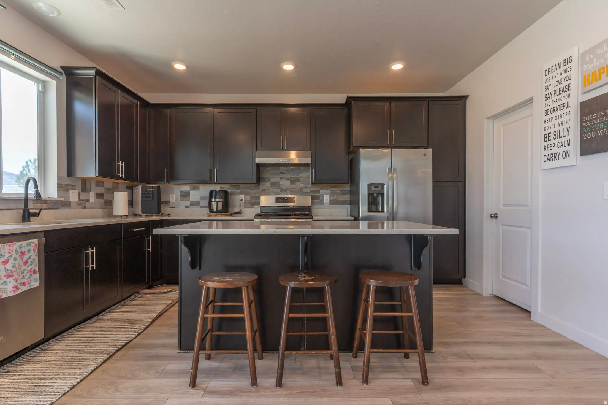 Kitchen featuring a breakfast bar area, dark wood finish cabinets, stainless steel appliances, a kitchen island, and recessed lighting